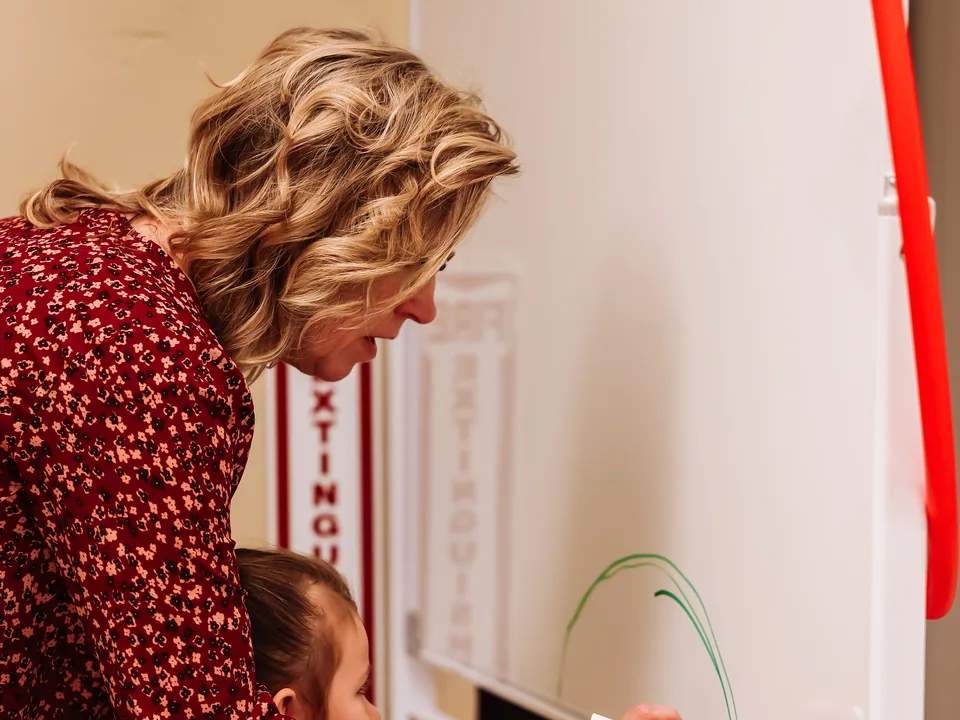 An occupational therapist guides a young child drawing arcs on a whiteboard at Brighten Pediatric Therapy in Hobbs
